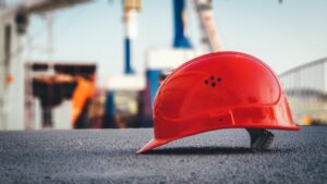 Close-up of a red hard-hat on the ground at a construction site.
