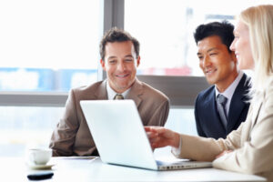 Three business professionals look at a laptop together